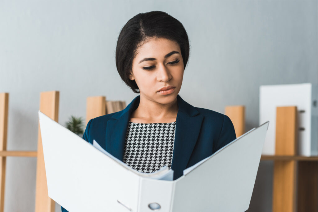 Femme experte relisant attentivement un document imprimé, illustrant la rigueur et la double révision conforme à la norme ISO 17100.