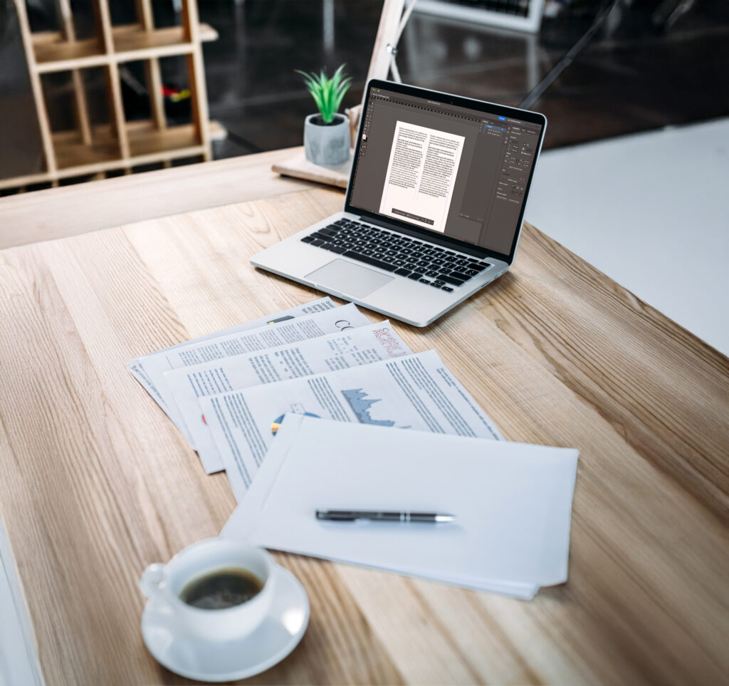 Bureau organisé avec un ordinateur et des dossiers print, illustrant l’intégration automatique des traductions dans les documents source et la gestion des supports print et digitaux.