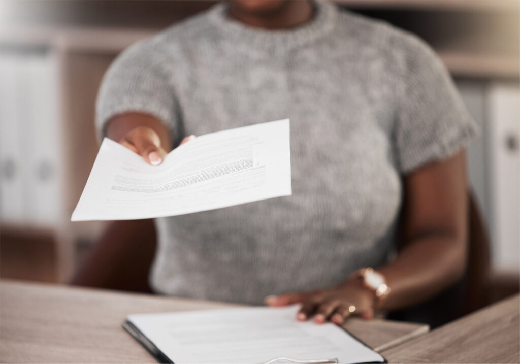 Personne assise dans un bureau remettant un document officiel traduit et certifié, illustrant les options de dépôt et de livraison à Bordeaux.
